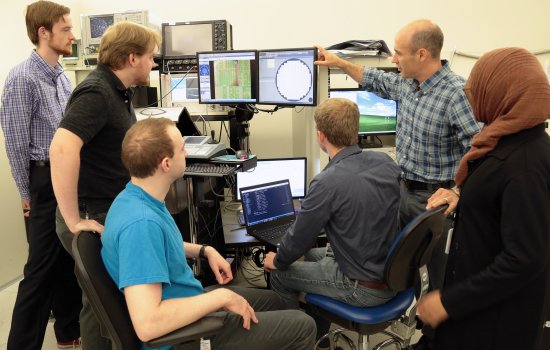 Students of Professor Nathaniel Cady, second from right, gather around a monitor of a semiconductor wafer in a lab at Albany Nanotech.