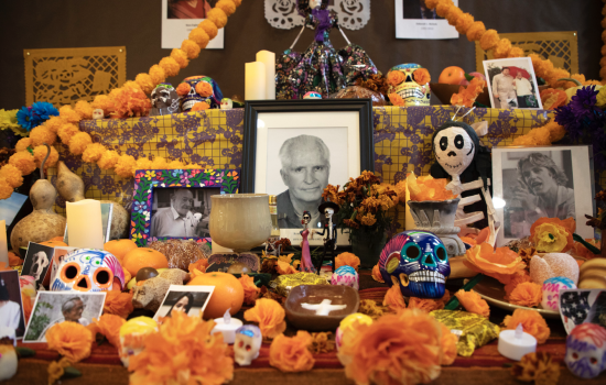 Candles, painted skulls, skeletons, garlands of orange paper marigolds and photos of deceased loved ones decorate a table in the Arts and Sciences building.