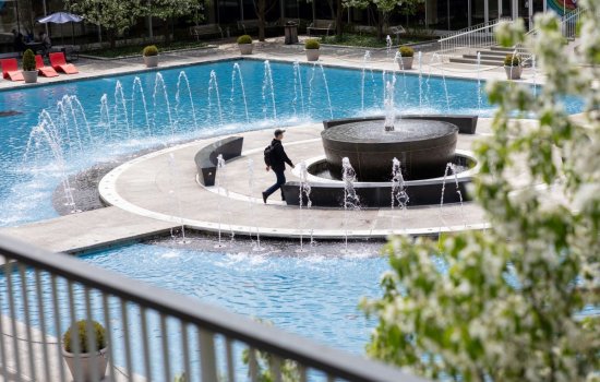 Student walking past uptown campus fountain