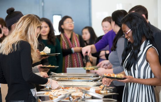 Campus community members line up to fill their plates during the ISSS Thanksgiving Dinner.