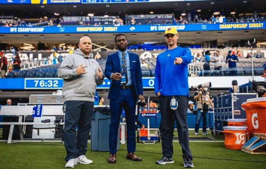Qadeer Morgan stands in the middle of two other Los Angeles Rams staff members on the field at SoFi Stadium.