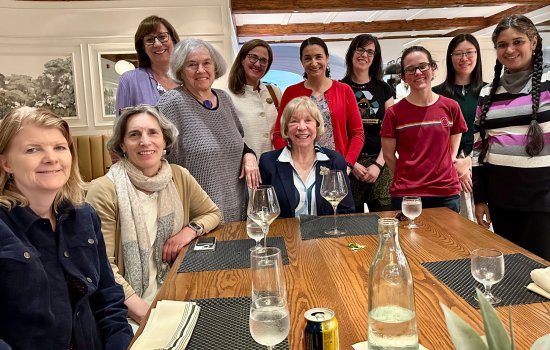 11 members of Women in Science and Health (WISH) pose for a photo around a restaurant table.