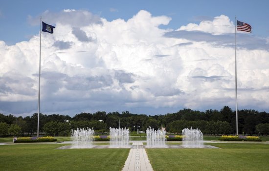 Flags wave in the wind and fountains spray water in the UAlbany entry plaza.