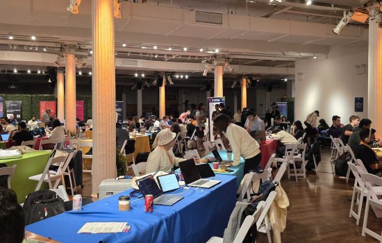 A spacious room filled with numerous people seated at tables, engaged in conversation and activities.