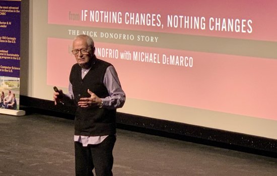 Nick Donofrio standing on stage and holding his hands out in front of him.