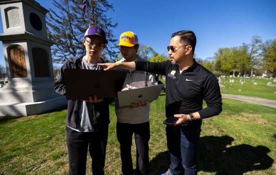 Students Weiming Lan and Micah Wang stand with professor Rui Li at the site of the Civil War memorial at Albany Rural Cemetary in Menands, N.Y.