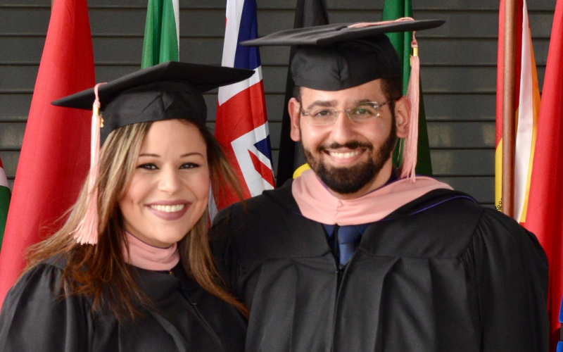 Mena and Mirna Hanna smile at the camera - they are wearing their graduation robes and hats.