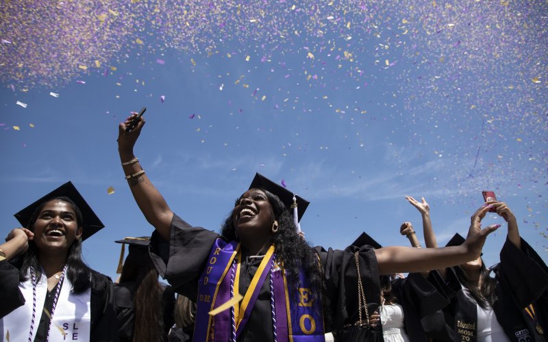New UAlbany graduates celebrate with purple and gold confetti at the 2023 undergraduate commencement ceremony.