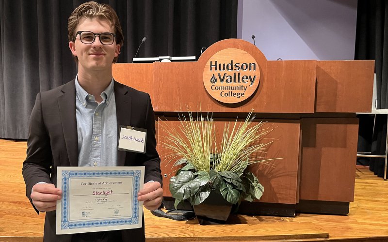 UAlbany student Jacob Webb stands with his award for first place at the Capital Region business competition. 