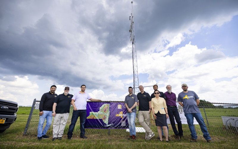 Mesonet researchers stand in front of the Lake Placid site on a cloudy day.