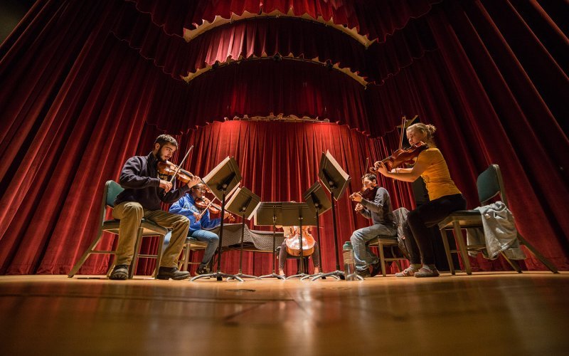 Five musicians play instruments on stage