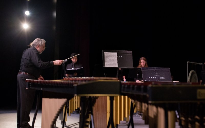 percussionists play music on stage with conductor