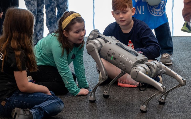 Young students watch a robotic dog in action at STEM and Nanotechnology Family Day at ETEC in February, 2024.