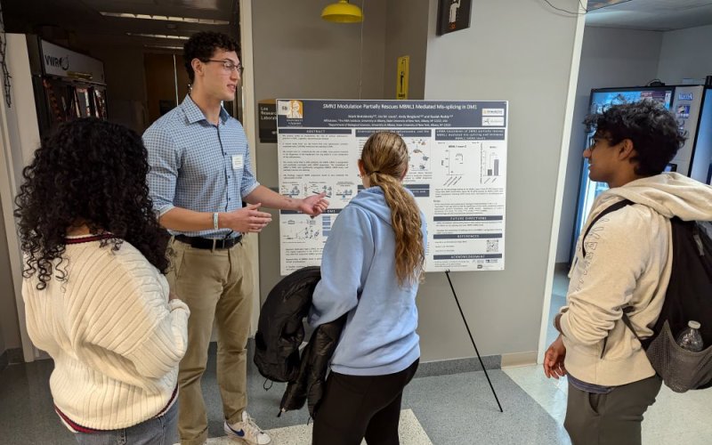 Mark-Bratslavsky at a poster session describing his project to three other students.