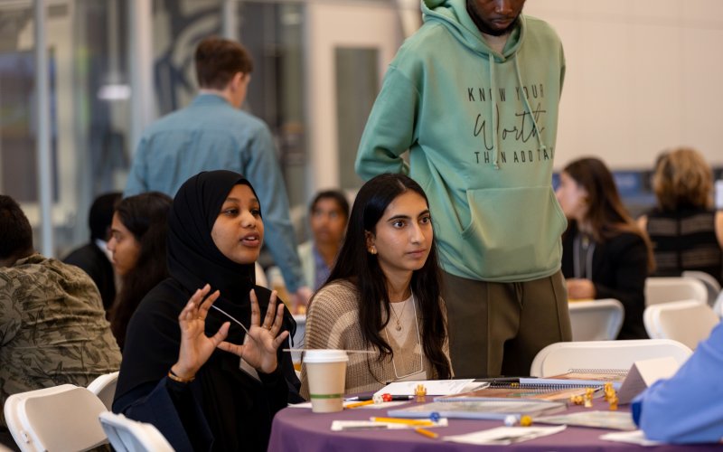 Two students engage in conversation during Research and Entrepreneurship Week at UAlbany in October, 2024. (Photo by Mario Sotomayor)