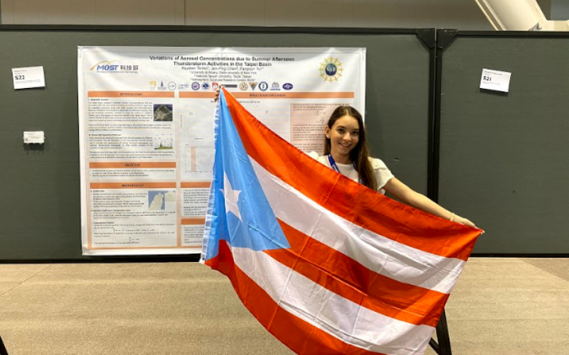 Kayleen Torres Maldonado displays the Puerto Rican flag in front of her research at the American Meteorological Society Annual Meeting in Boston, January 2020.