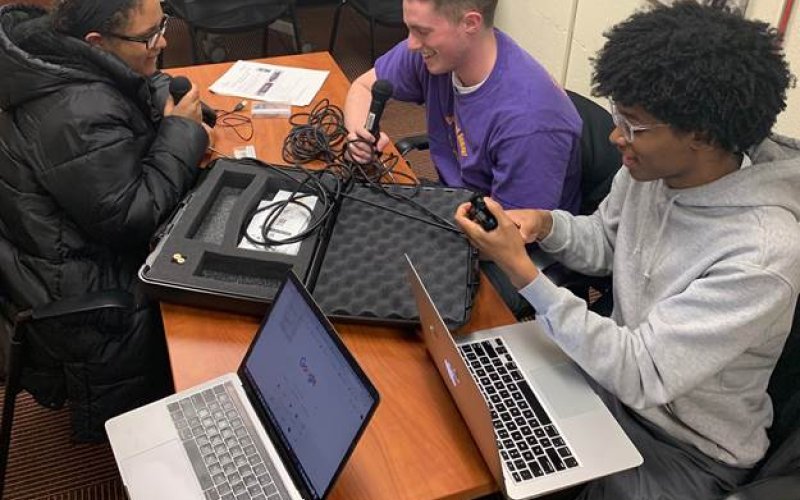 Students with laptops and microphones recording podcasts.