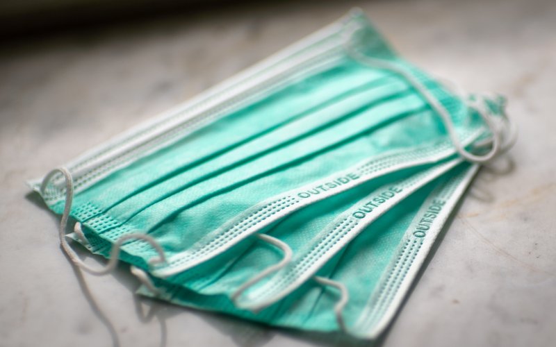 Three blue-green face masks sit on a grey surface.