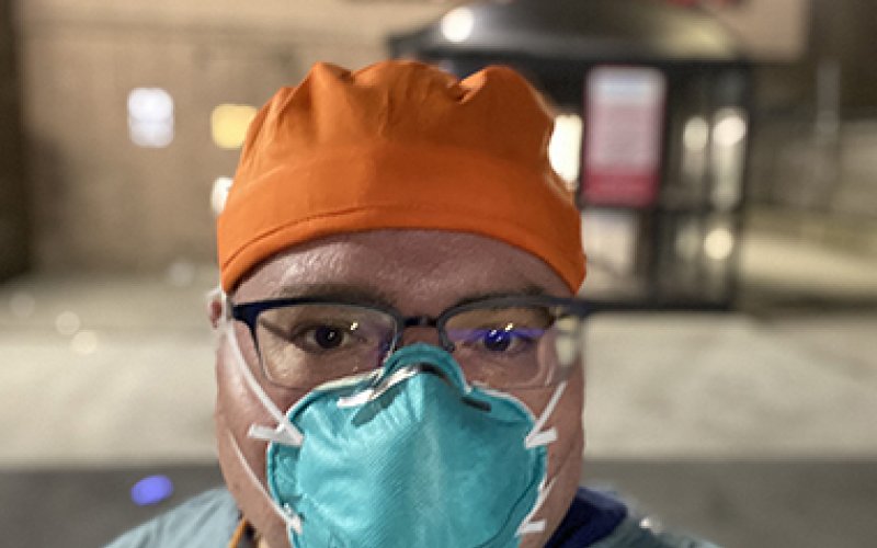 MPH student Dr. Lou Rotkowitz stands in front of a Queens emergency room in scrubs and a mask