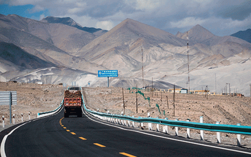 Truck driving up a road with mountains in distance