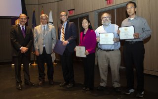 Winners of the President's Excellence Award for Research and Creative Activities pos, holding their certificates, with the President