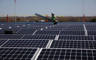 A crew member is seen installing panels on the roof of the University at Albany academic podium.