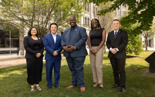 SUNY SA leaders stand on the grass in front of the SUNY System Administration Building.