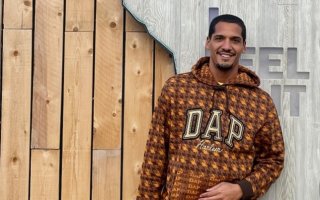 Orion Artis stands in front of wood fence at an outdoor event 