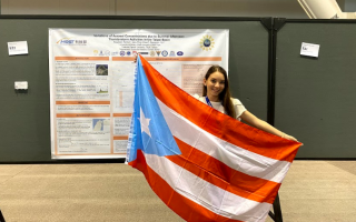 Kayleen Torres Maldonado displays the Puerto Rican flag in front of her research at the American Meteorological Society Annual Meeting in Boston, January 2020.