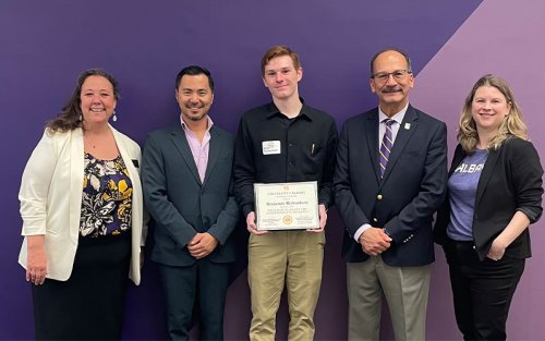 Benjamin Richardson stands with UAlbany President Havidán Rodríguez, Rui Li and others while holding the 2024 President Award for Undergraduate Research