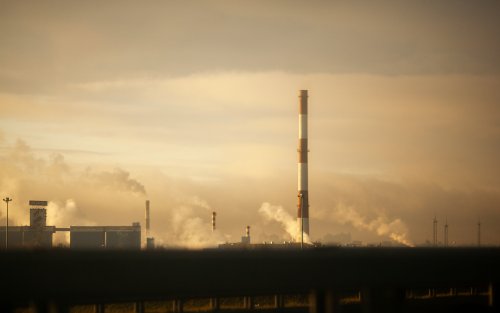 Smoke from a factory rises into the atmosphere on a cloudy day. 