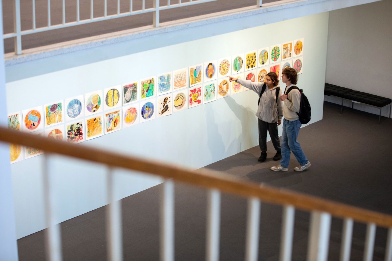 Two students admire artwork mounted on the wall inside the University Art Museum during UAlbany Showcase.