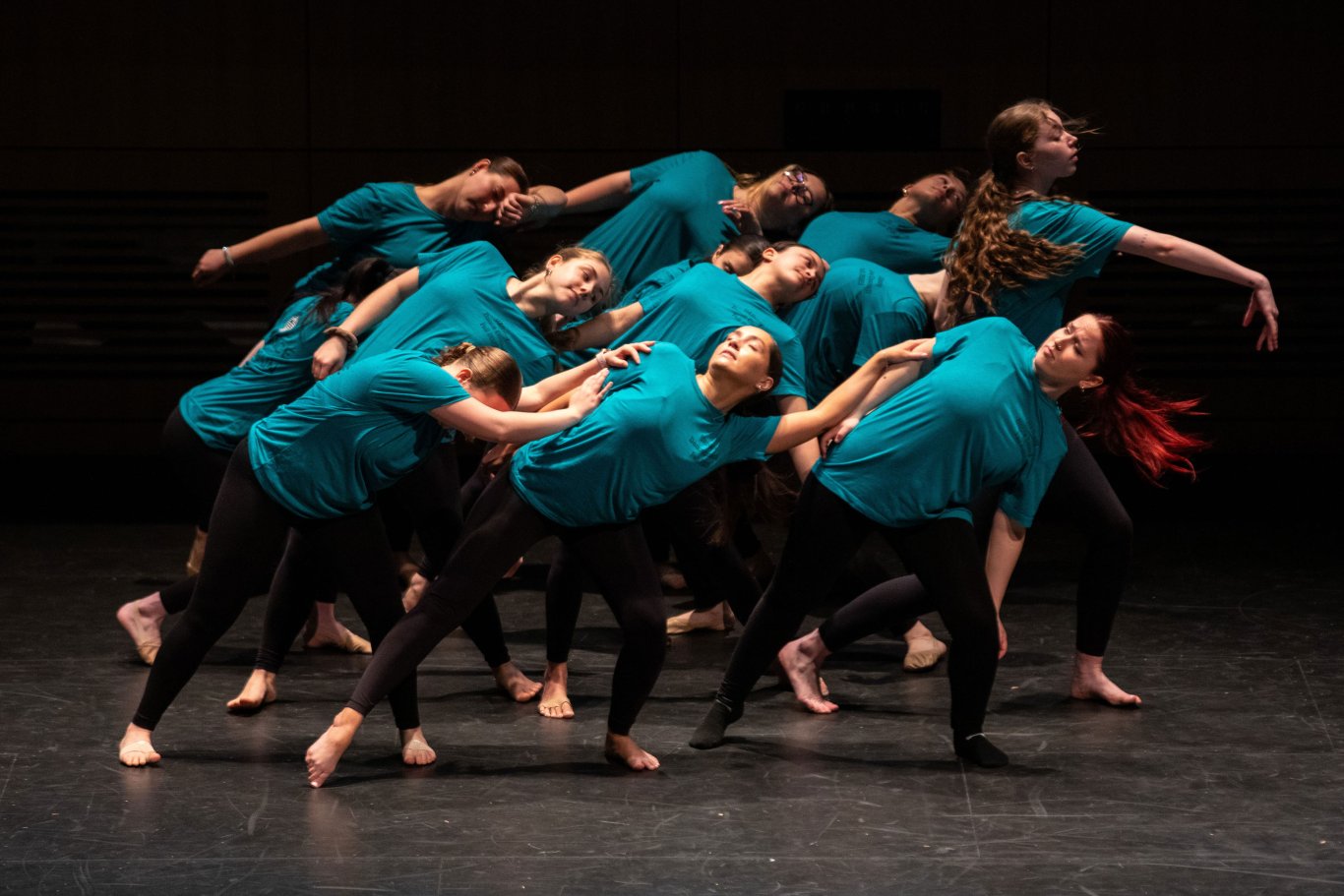 A dance troupe in matching costumes dances on stage in unison at UAlbany Showcase.