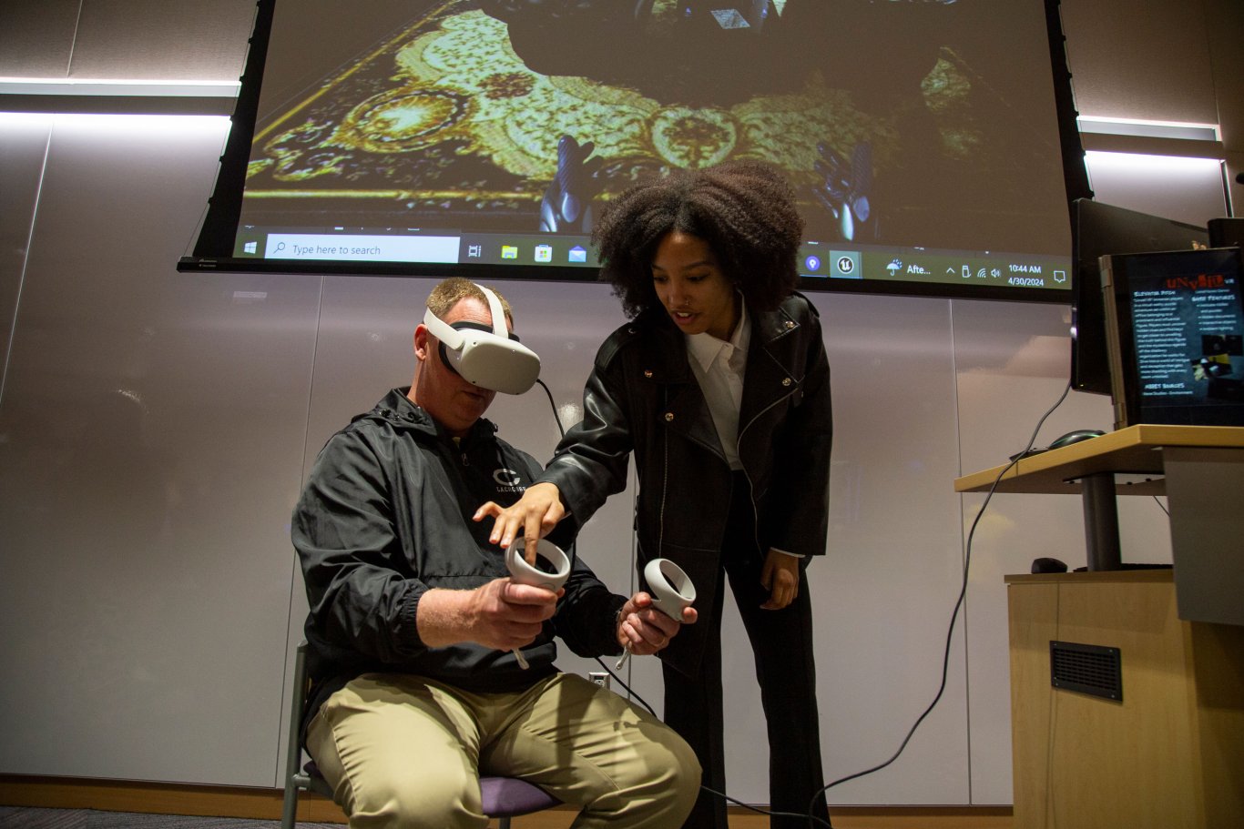 A student helps a Showcase Day attendee use a virtual reality headset.