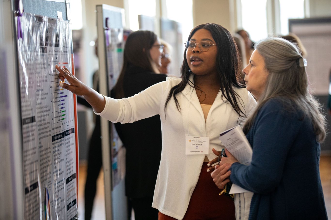 A student points to their research poster while speaking with a UAlbany Showcase attendee.