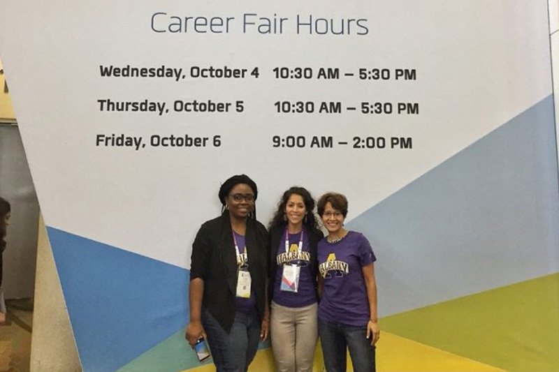 3 people standing in front of a grace hopper celebration sign