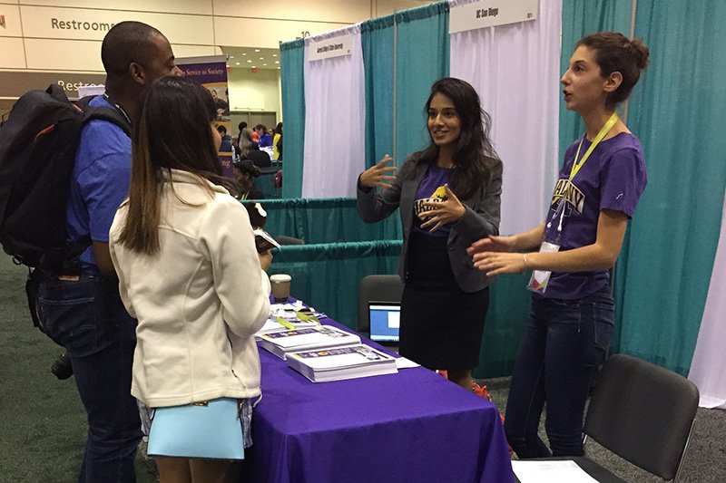 two people answering a question from visitors to their expo table