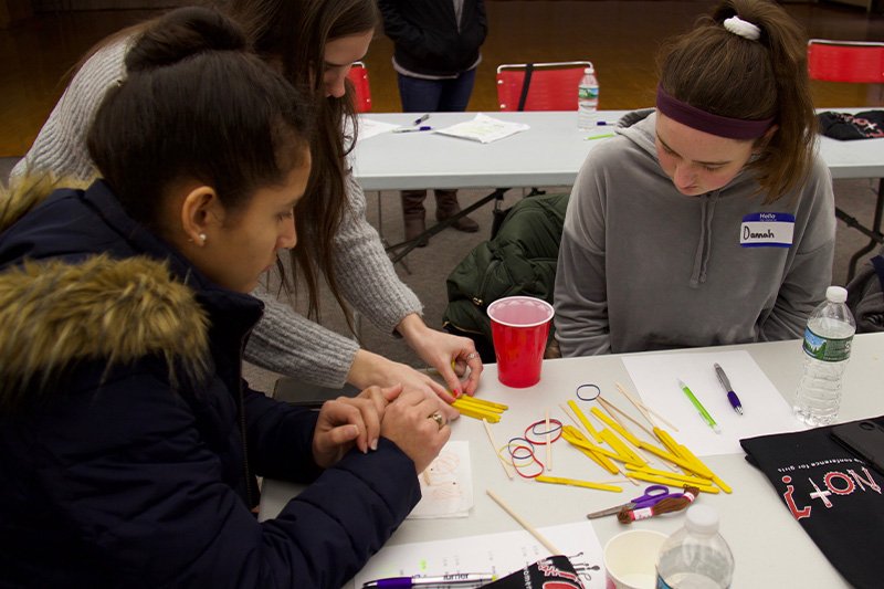 a group of 2 students with the help of an aide work on a project