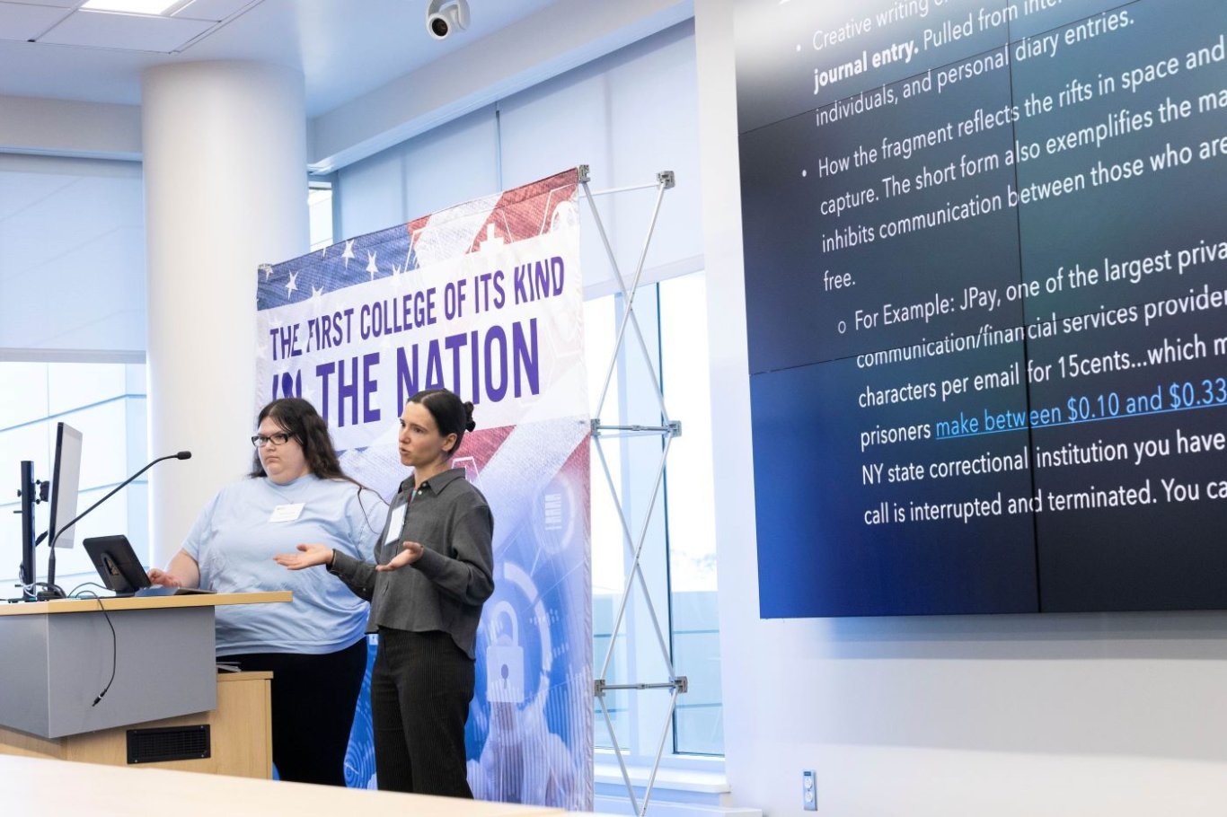 Two students speaking at a podium about their project.