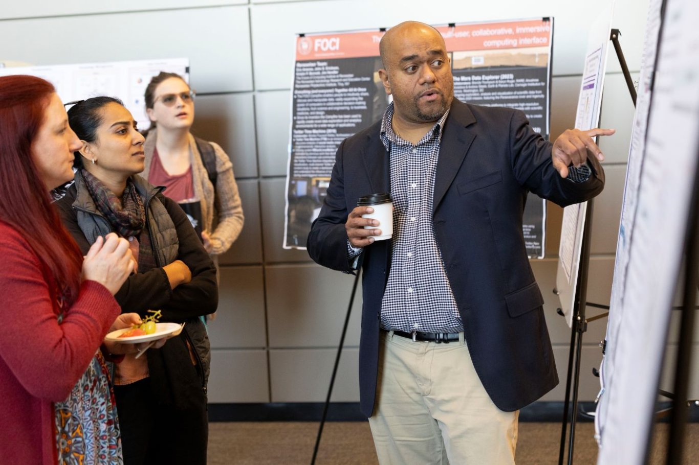 Poster presenter speaking with a small group of on lookers.