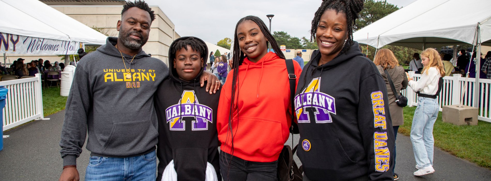 Four family members wearing UAlbany sweatshirts smile and pose for a photo during Great Dane Family Weekend.