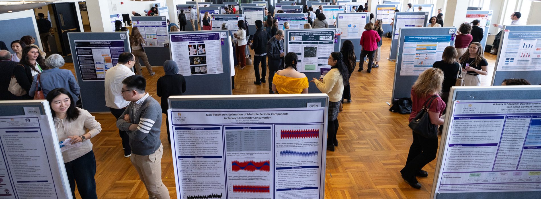 Dozens of students present research posters to attendees inside an exhibition space during UAlbany Showcase.