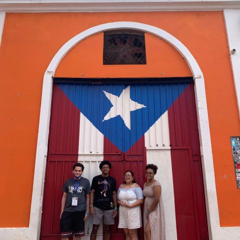 HVCC EOP student Stefan Warner, UAlbany EOP student Omahri Sturdivant, HVCC EOP student Astrid Fuentes-Dimas and UAlbany EOP student Ashlye Reyes pose for a photograph in front of a mural of the Puerto Rican flag. 