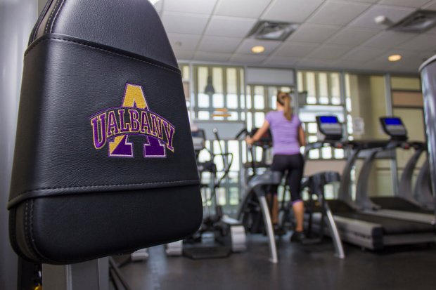 A student uses an elliptical machine inside a fitness center.