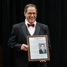 man in tuxedo holding plaque