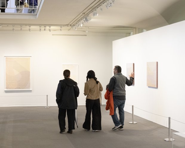 Three museum visitors looking at artwork