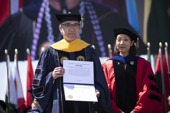 Jürgen Popp stands with Provost Carol Kim after being presented with an honorary degree at UAlbany's 2023 undergraduate commencement ceremony.