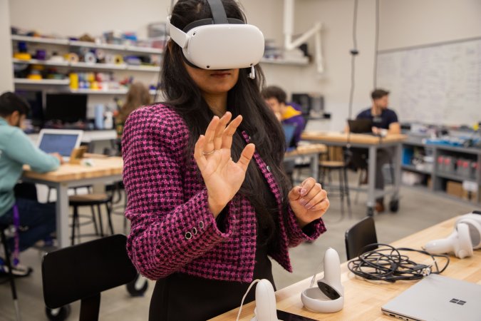 A student wears a virtual reality headset from inside the CEHC Makerspace.