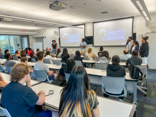 A full room of students watch a presentation during an AMA general interest meeting on campus.