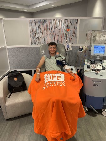 Jayden Elston sits under an orange blanket while donating stem cells at the Gift of Life Collection Center in Boca Raton, Fla.